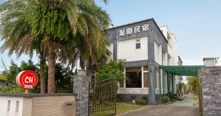 晨園景觀民宿｜入口棕櫚樹與民宿建築